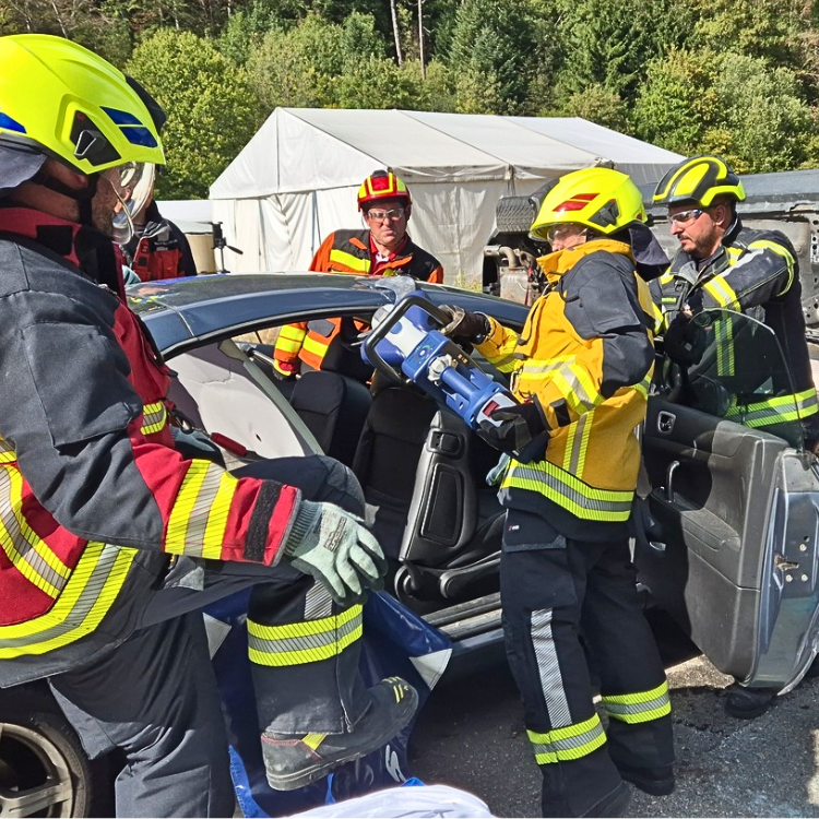 Feuerwehrleute schneiden ins Autodach mit der LUKAS E4 Rettungsschere